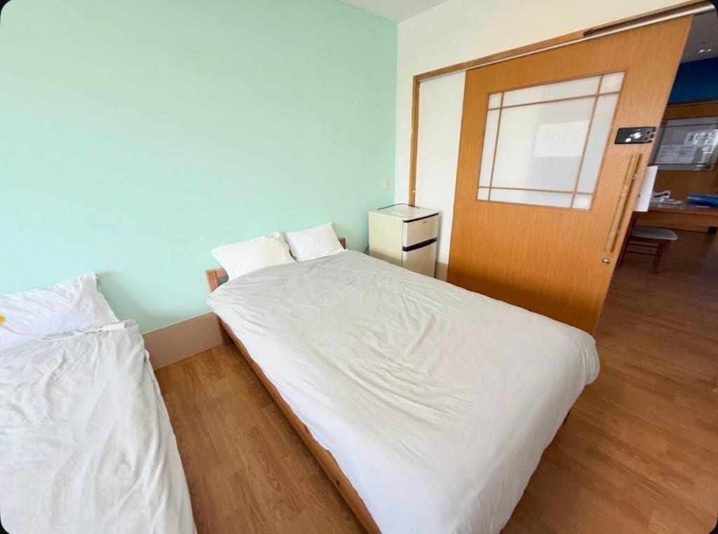 Een enkel bed met houten frame, een nachtkastje en een klein kastje.