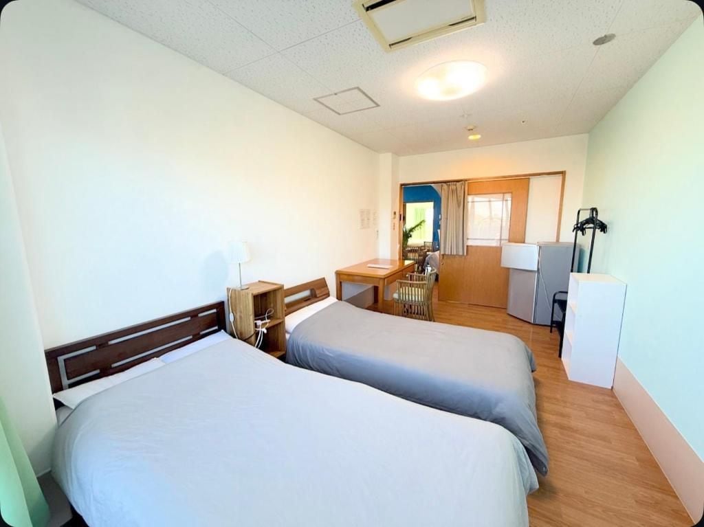 A hotel room with two beds, a desk, a chair, and a small table.