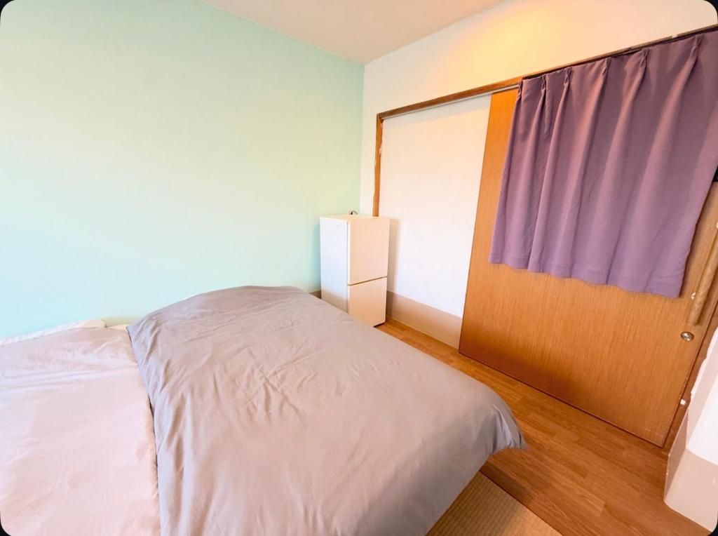 A bedroom with a bed, a wardrobe, and a small bedside table.