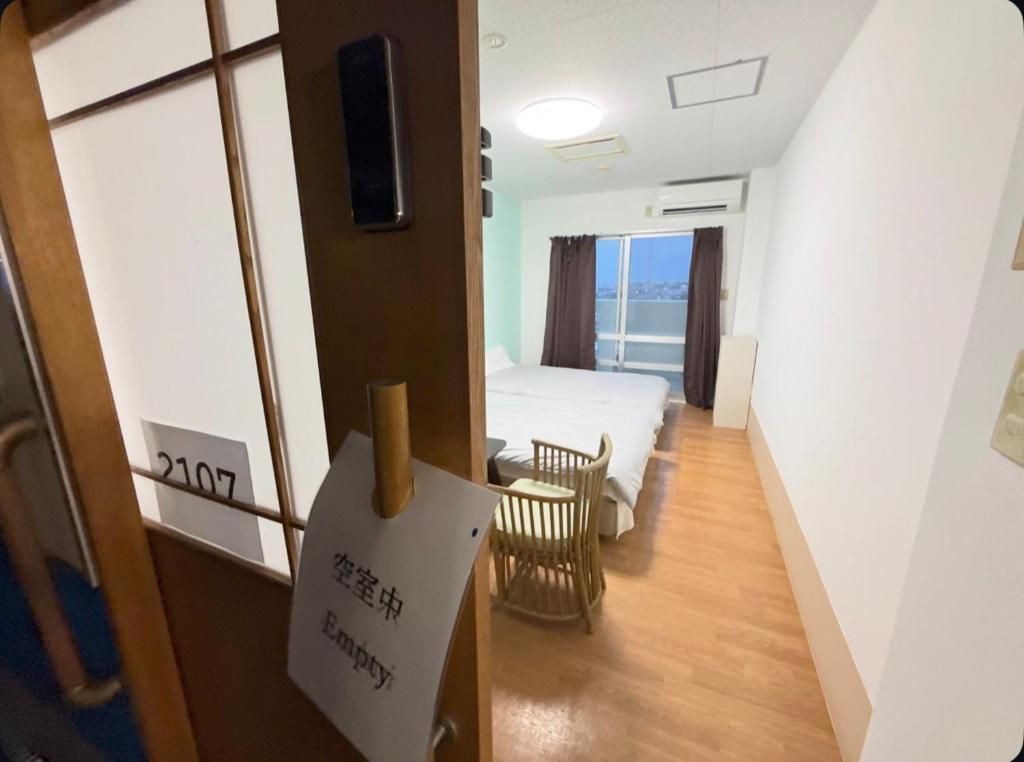 A hotel room with a bed, a chair, a small table, and a sign indicating the room is empty.