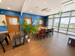 A conference room with a large table, chairs, a potted plant, and a view through large windows.