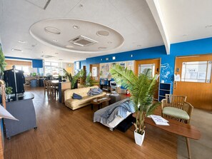 A hotel lobby with a reception desk, seating area, and a large plant.