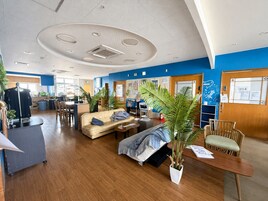 Un vestíbulo de hotel con mostrador de recepción, zona de estar y una planta grande.
