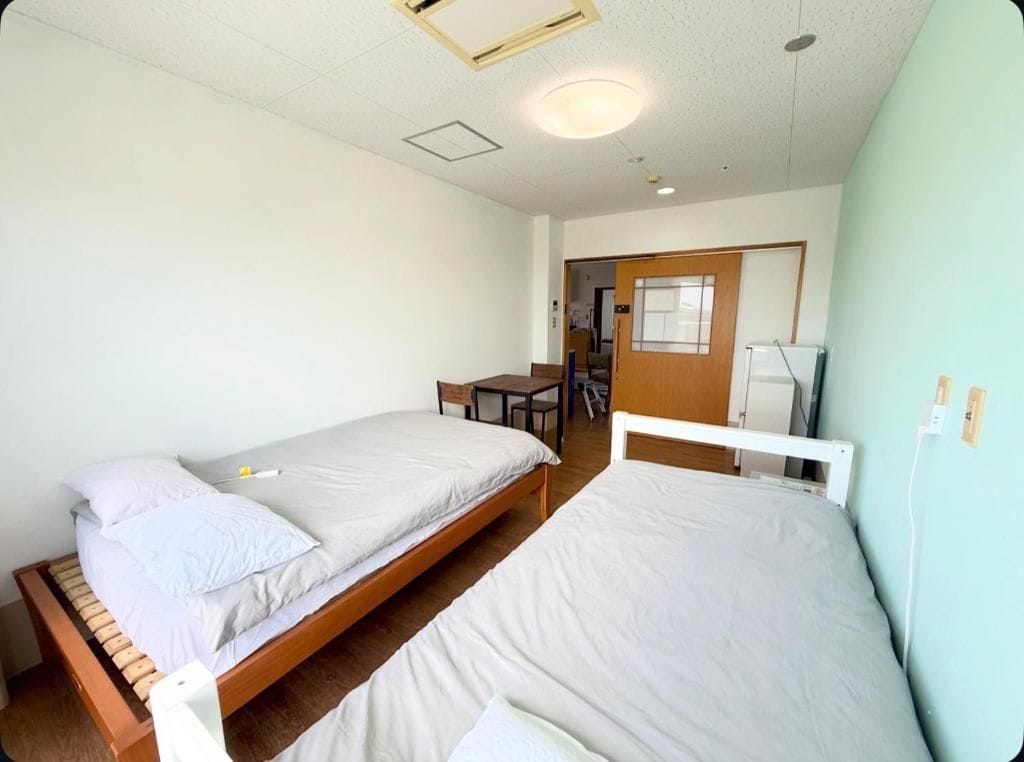 A room with two beds, a desk, and a chair.