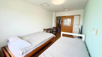 A room with two beds, a desk, and a chair.