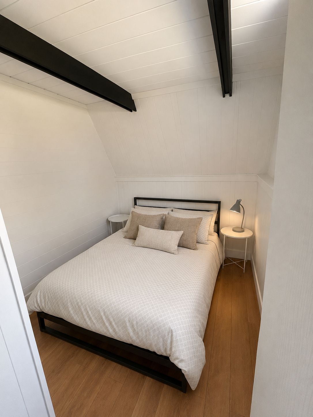 A bedroom with a bed, two bedside tables, and a lamp.