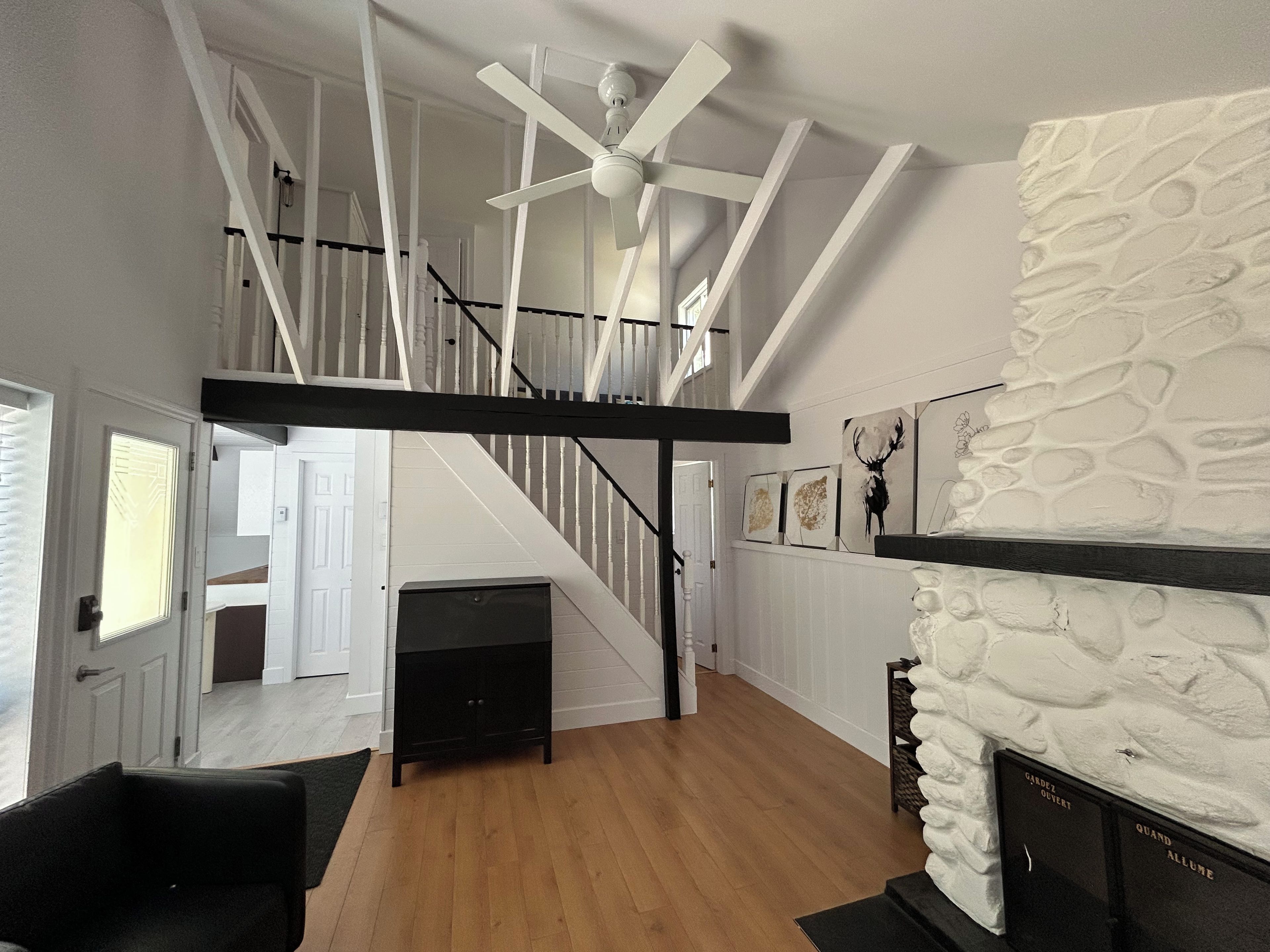 A modern interior with a staircase, a fireplace, and artwork on the walls.