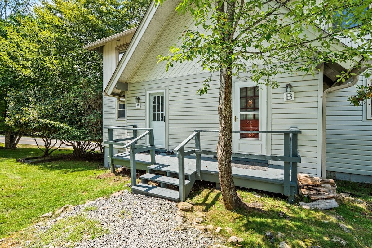 A two-story house with a porch and a staircase leading to the entrance.
