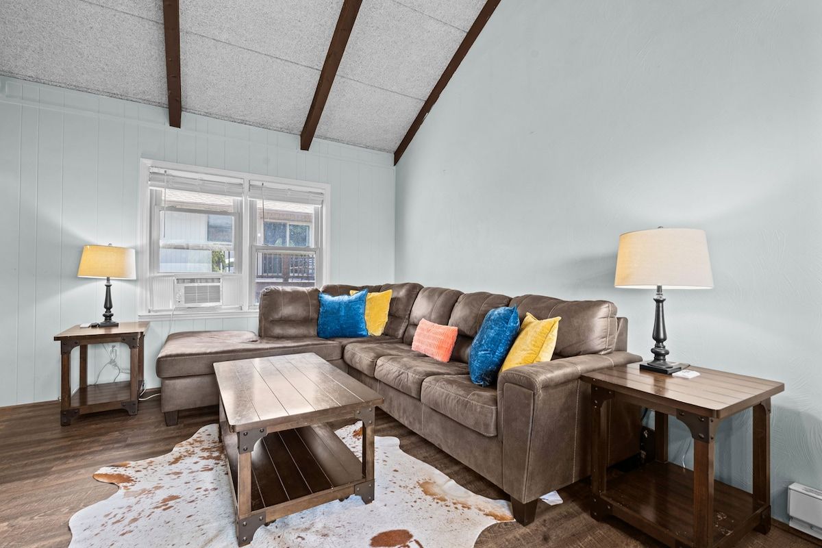 A living room with a sectional sofa, two side tables, a wooden coffee table, and a cowhide rug.