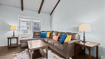 A living room with a sectional sofa, two side tables, a wooden coffee table, and a cowhide rug.