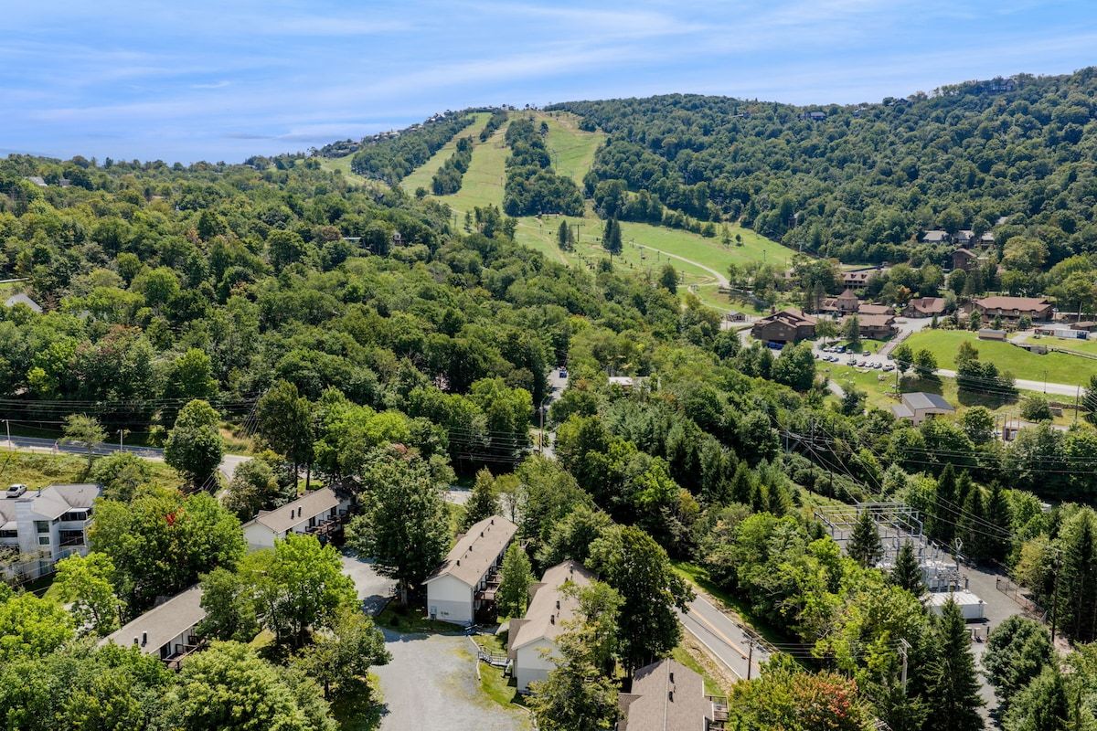 A residential area with houses, roads, and a hilly landscape in the background.
