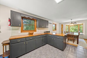 A kitchen with dark cabinets, a wooden countertop, and a built-in oven. - Cozy High Country Cabin Near Banner Elk (Banner Elk)