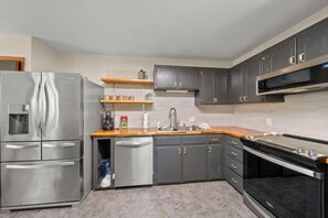 A modern kitchen with stainless steel appliances, grey cabinetry, and a wooden countertop. - Cozy High Country Cabin Near Banner Elk (Banner Elk)