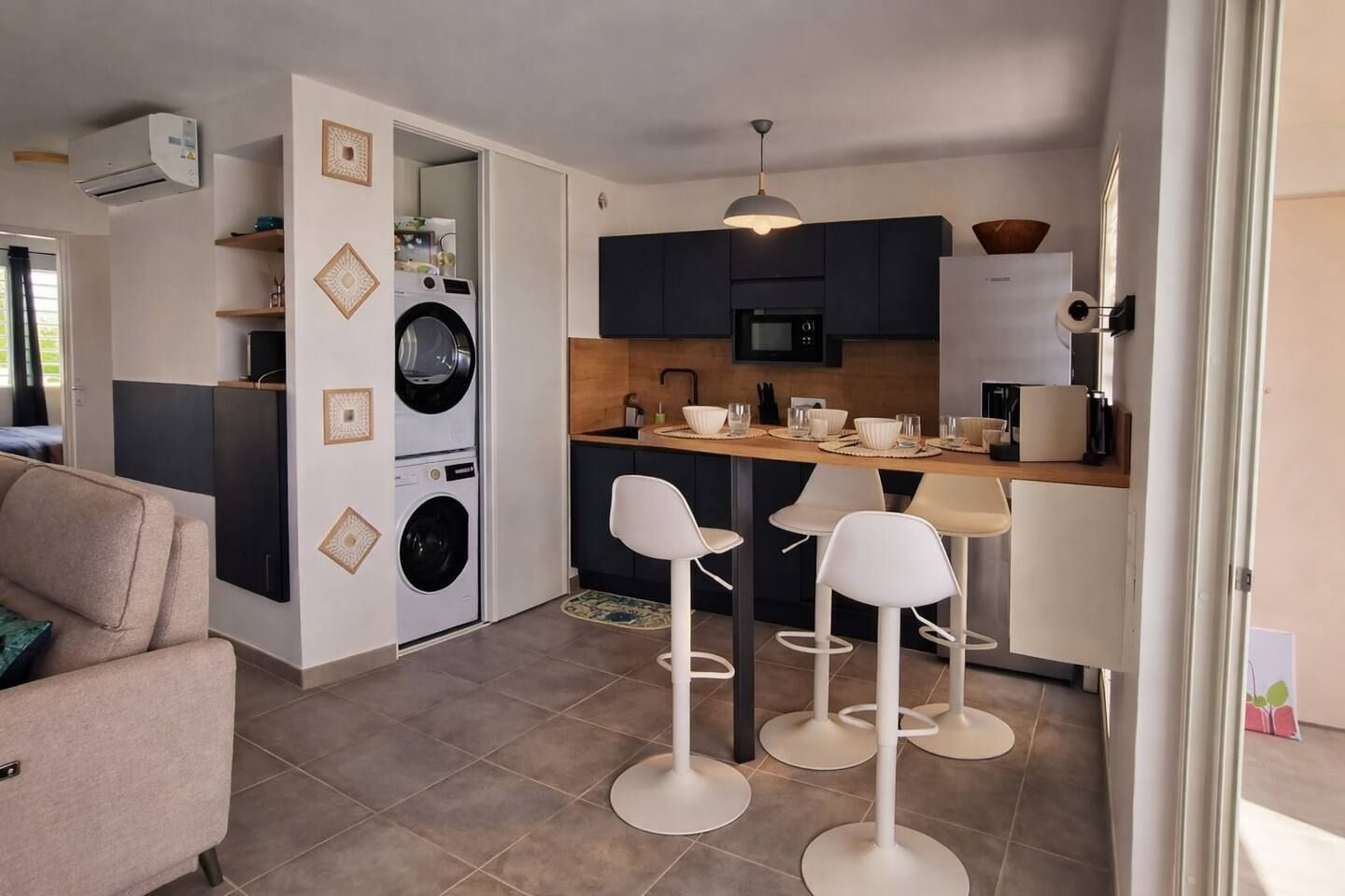 A compact living space with a kitchenette, a washing machine, and a dining area with bar stools.