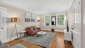 A living room with a sofa, coffee table, floor lamp, and artwork on the wall. - Mins to Downtown, Jackson Hosp., ASU, Maxwell AFB (Montgomery)