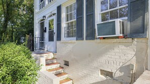 A white building with a brick base, a front door, and a small set of steps leading to the entrance. - Mins to Downtown, Jackson Hosp., ASU, Maxwell AFB (Montgomery)