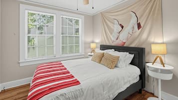 Een slaapkamer met een bed, twee bedlampen, een raam met zonwering en een plafondventilator.