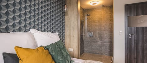 A hotel room with a bed, a shower area, and a door.