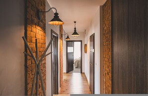 Ein Flur mit freiliegenden Backsteinwänden, Holzdielen und schwarzen Metallgeländern.