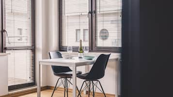 A dining area with a table, chairs, a bottle of wine, and a bowl.