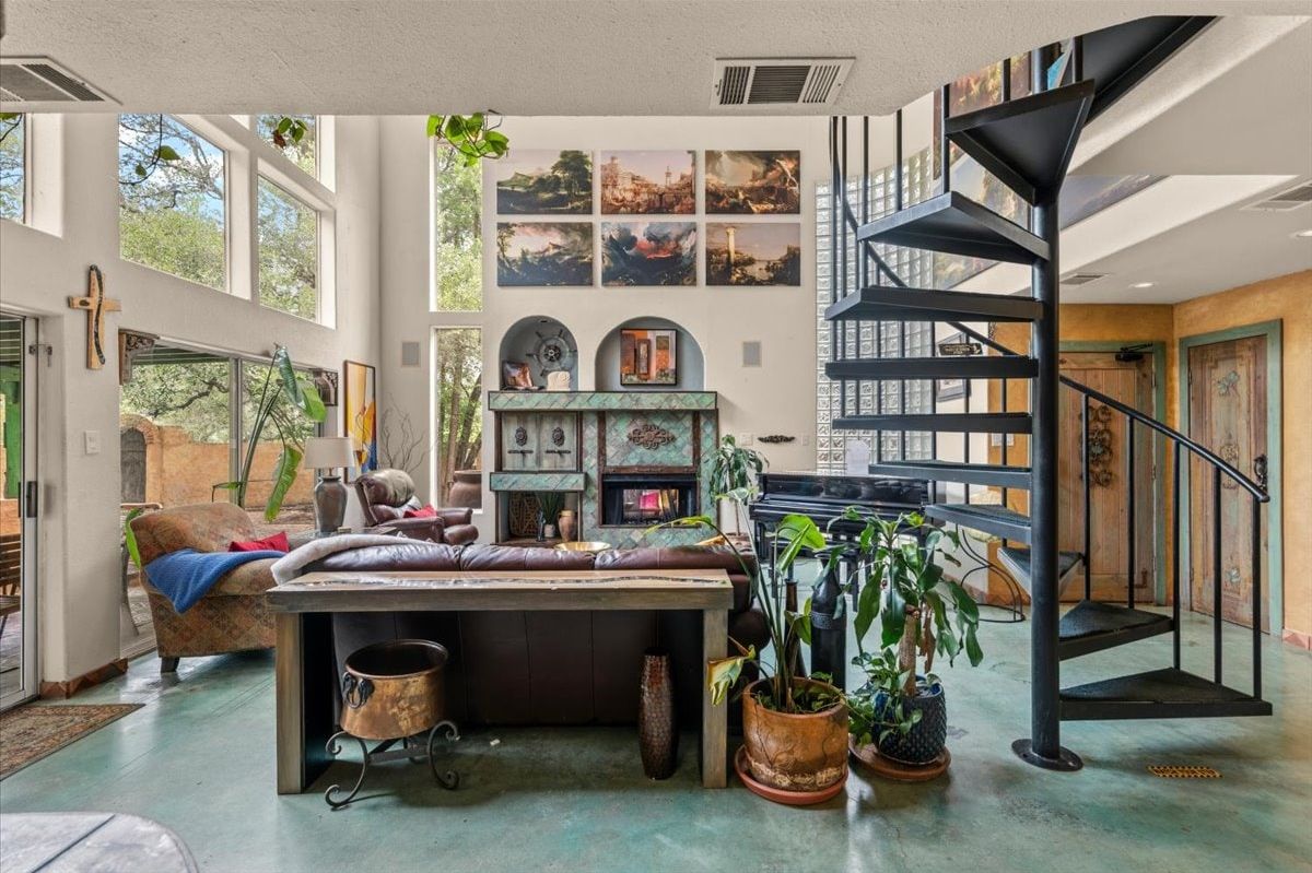 A spacious living area with a fireplace, a staircase, and a view of the outdoors.