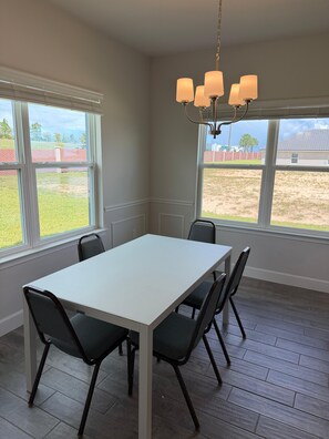 A room with a white table and four chairs, large windows, and a chandelier. - Villa Wonderlands! in the CENTRAL FLORIDA INNOVATION DISTRIC 30 MIN FROM DISNEY! (Auburndale)