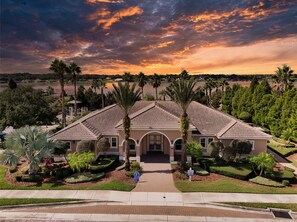 A two-story house with a tiled roof, surrounded by palm trees and a well-maintained lawn. - Villa Wonderlands! in the CENTRAL FLORIDA INNOVATION DISTRIC 30 MIN FROM DISNEY! (Auburndale)
