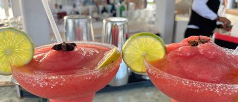 Two drinks with lime slices and star anise garnishes on a bar counter.