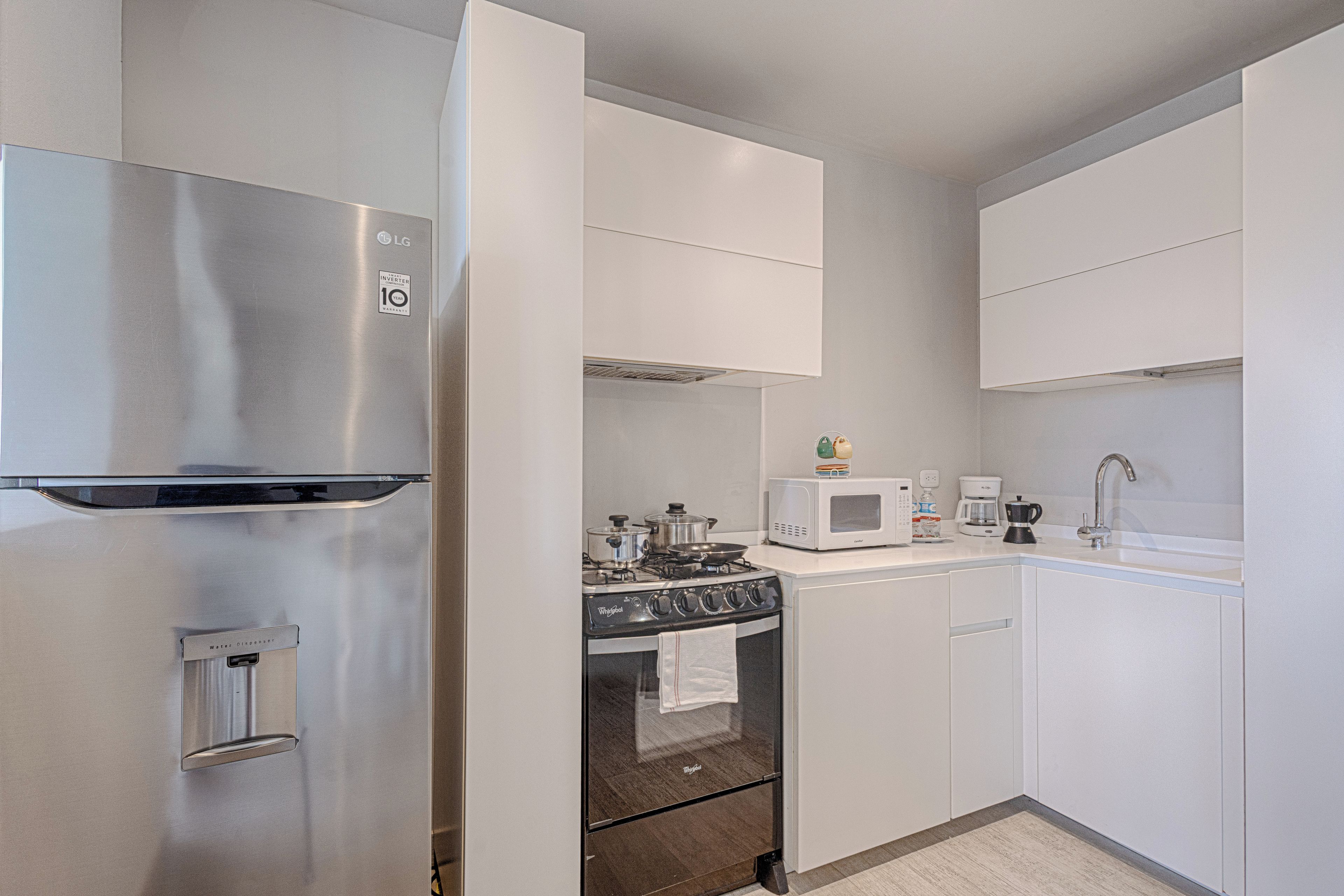 A modern kitchen with stainless steel appliances, a built-in oven, and white cabinetry.