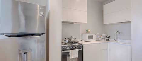 A modern kitchen with stainless steel appliances, a built-in oven, and white cabinetry.