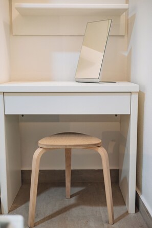 Un escritorio blanco con una laptop y un taburete de madera.