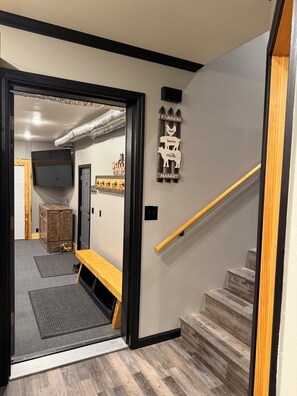 A staircase with a wooden handrail and a wall-mounted sign listing farm products. - Spacious 3-bedroom 2 living apartment with Alaska theme. TV’s in every room. (North Pole)