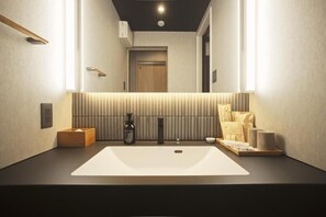 A modern bathroom with a large mirror, a white sink, and a towel rack. - Amu  (Beppu)