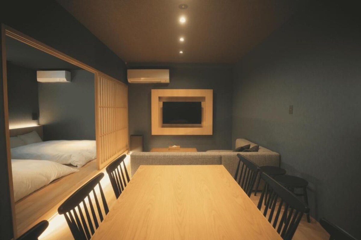Een compacte hotelkamer met een bed, een eettafel, stoelen, een televisie en een airconditioning.
