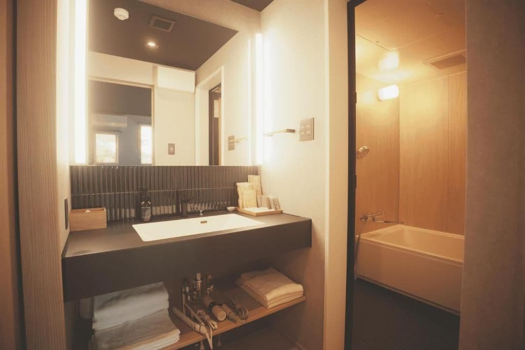 A modern bathroom with a large mirror, a bathtub, and a vanity with a sink.