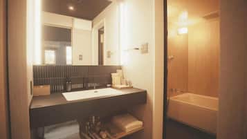 A modern bathroom with a large mirror, a bathtub, and a vanity with a sink.