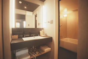 A modern bathroom with a large mirror, a bathtub, and a vanity with a sink. - Amu  (Beppu)
