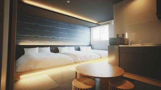 A modern hotel room with a large bed, a dining table, and a kitchen area. - Amu  (Beppu)