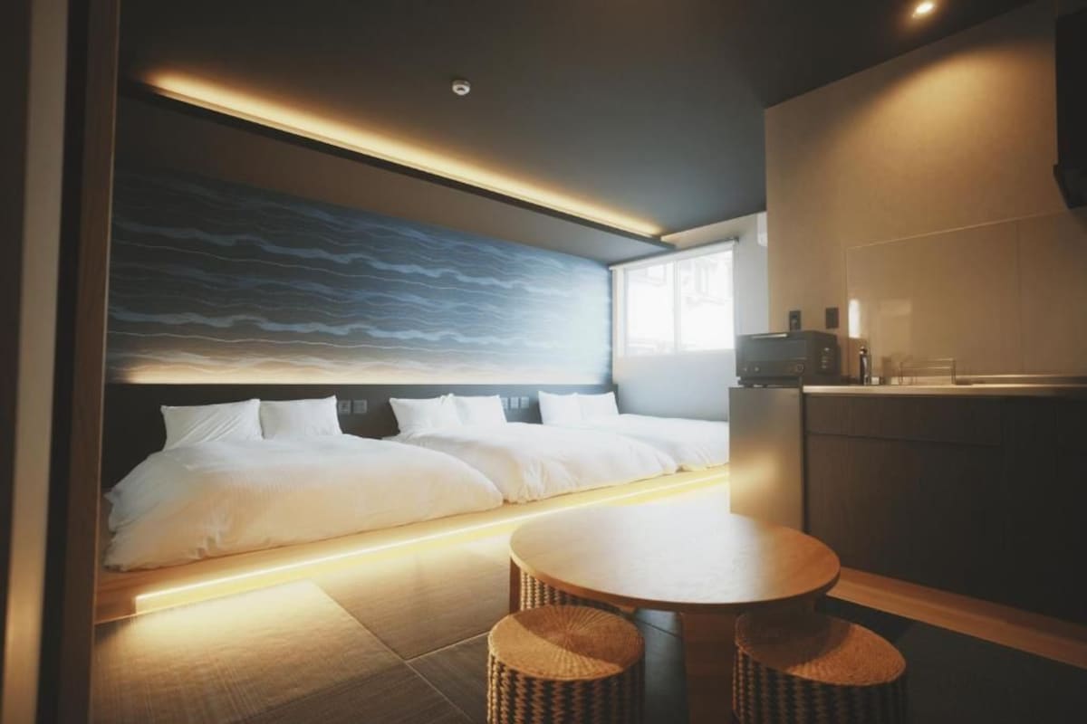 Een moderne hotelkamer met een groot bed, een eettafeltje en een kitchenette.