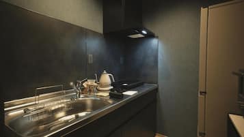 A modern kitchen with a stainless steel sink, a kettle, and a range hood.