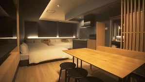 A modern bedroom with a bed, bedside tables, and a wooden dining table with chairs. - Amu  (Beppu)