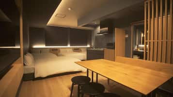 A modern bedroom with a bed, bedside tables, and a wooden dining table with chairs.