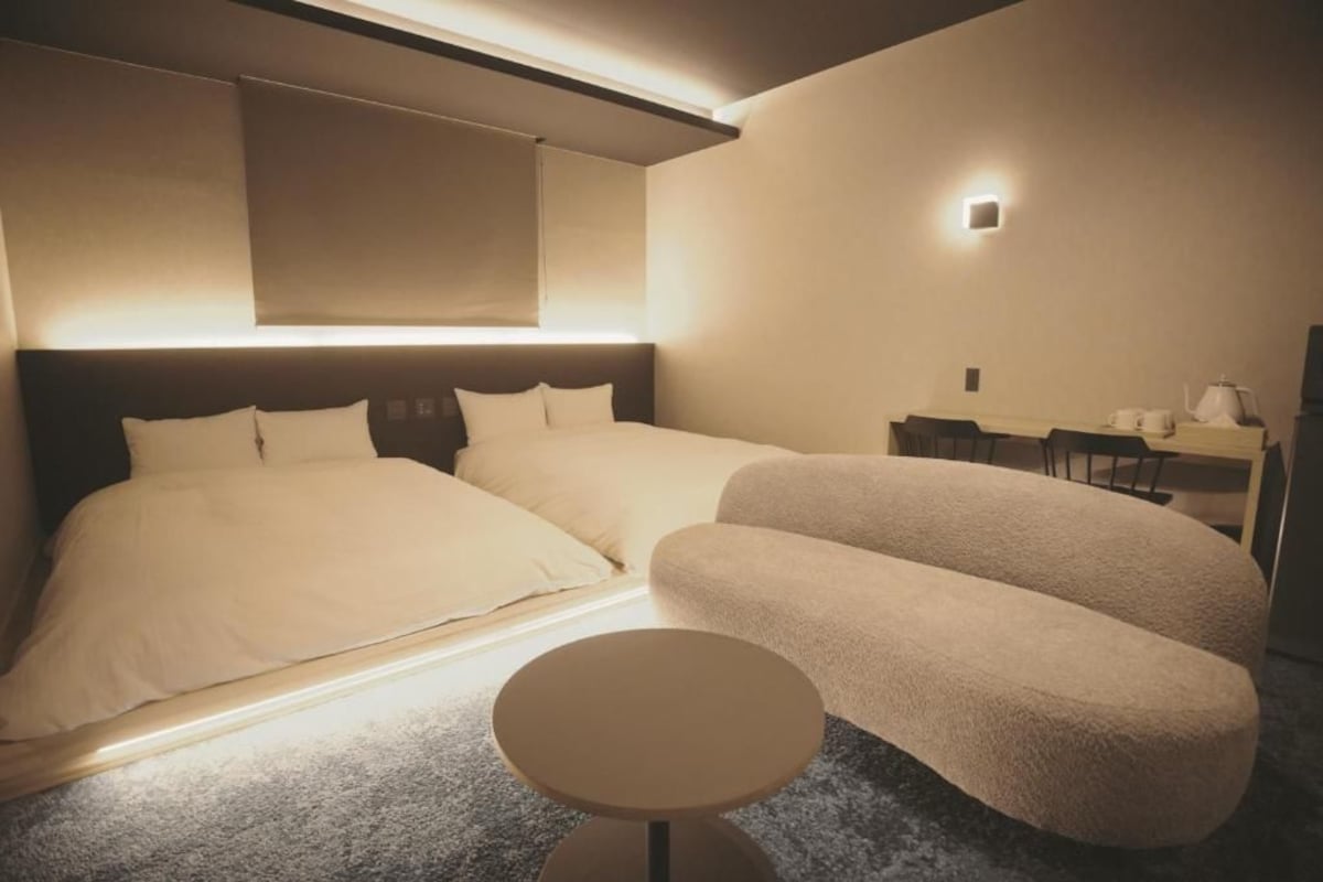 Een hotelkamer met een groot bed, een slaapbank, een klein rond tafeltje en een bureau met stoel.