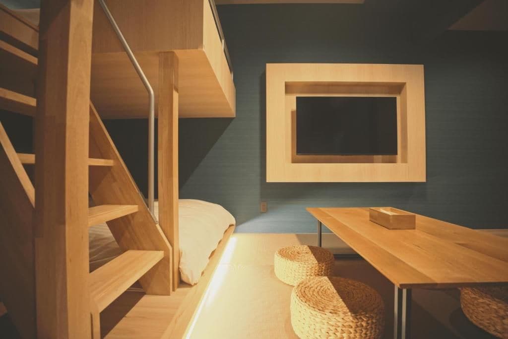 Quarto com beliche, escrivaninha e televisão fixada na parede.