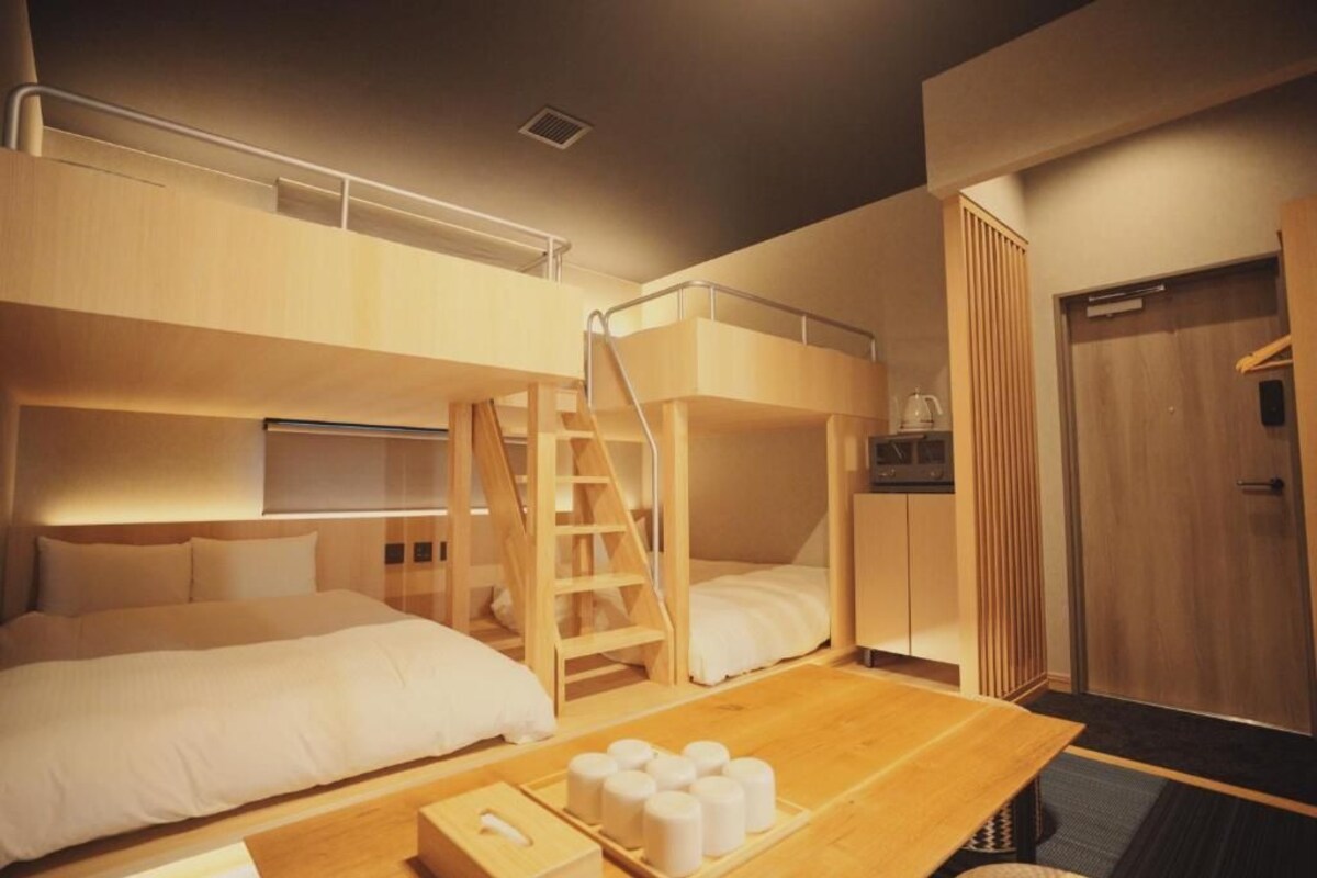 Een hotelkamer met stapelbedden, een houten tafel met toiletartikelen en een kledingkast.