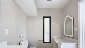 A bathroom with a toilet, sink, mirror, and a window. - Northshore Waterfront Resort (Port Charlotte)