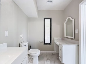 A bathroom with a toilet, sink, mirror, and a window. - Northshore Waterfront Resort (Port Charlotte)
