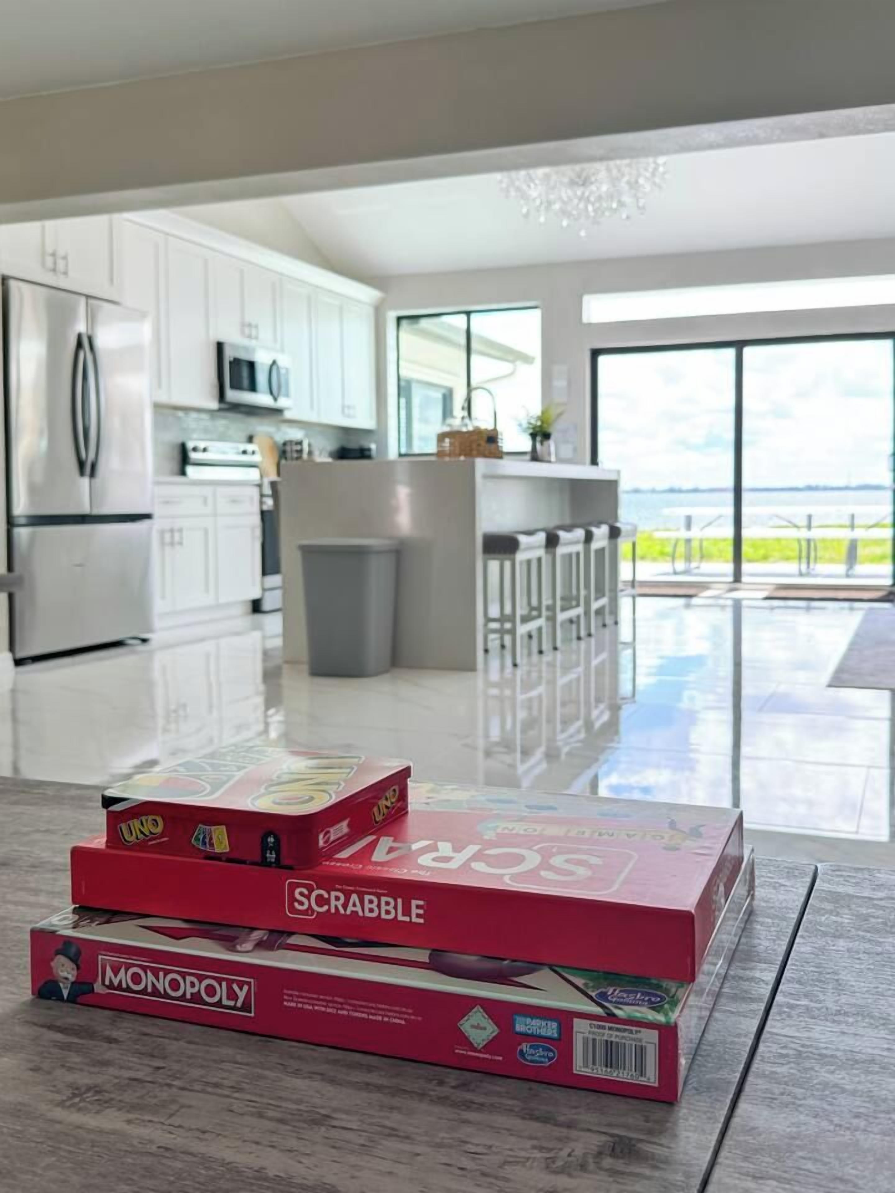 A modern kitchen with white cabinets, a stainless steel refrigerator, and a bar area with stools.
