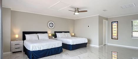 A bedroom with two beds, a ceiling fan, a clock, and a stained glass window.