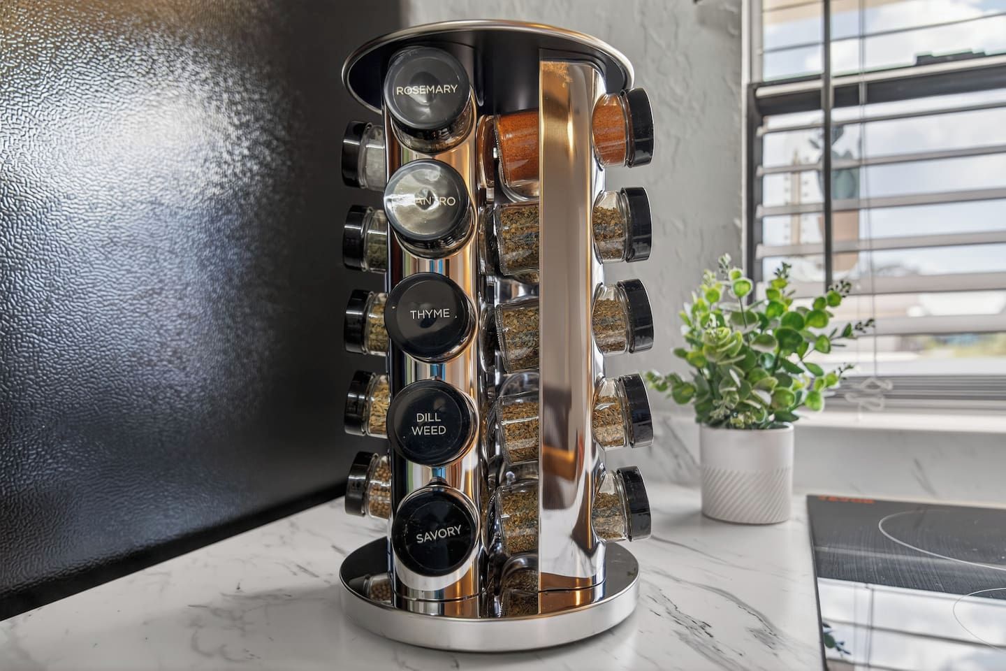 A kitchen with a spice rack containing labeled containers for rosemary, anise, thyme, dill weed, and savory.